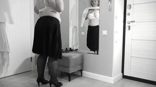 A mature, fat milf with big, saggy tits is changing clothes in front of the mirror.
