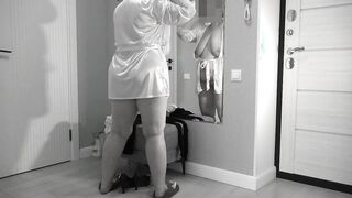 A mature, fat milf with big, saggy tits is changing clothes in front of the mirror.